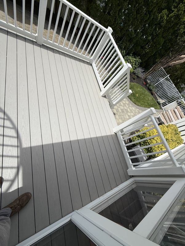 Gray composite deck with white railings, looking out to the yard