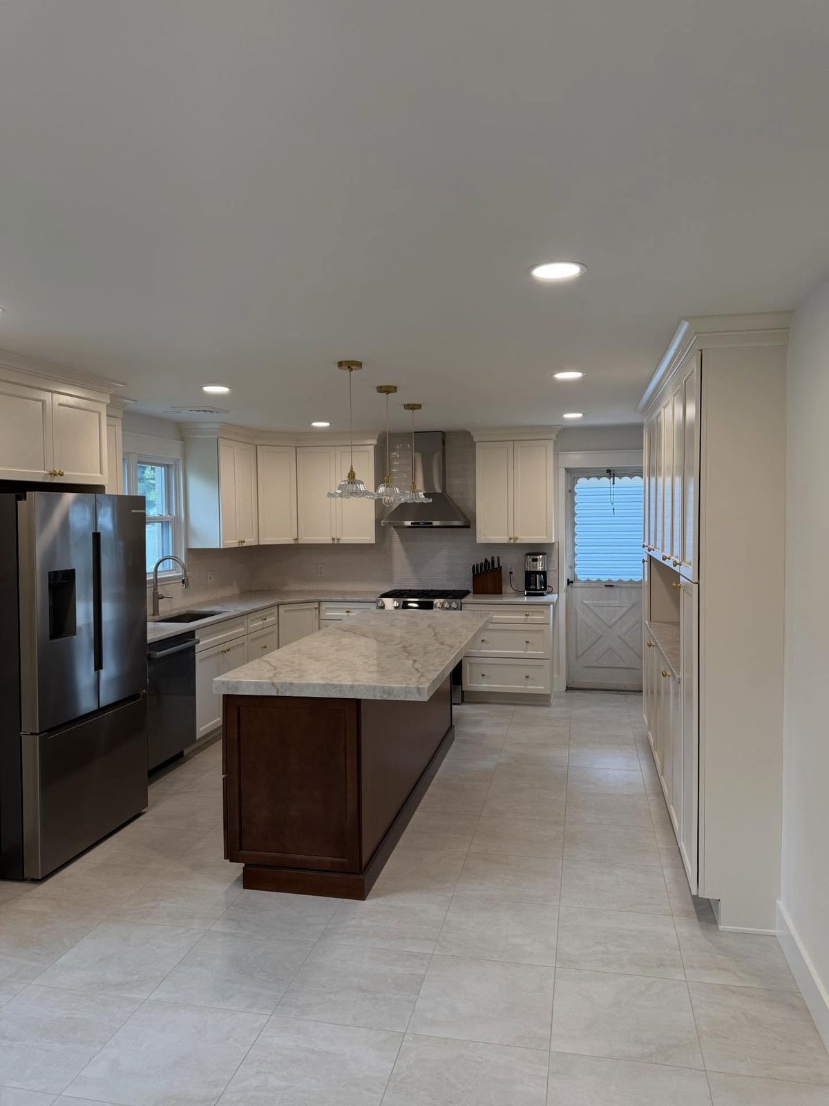 Finished open kitchen with a wall removed to join the kitchen and dining room, an 8-foot dark-wood island, white shaker cabinets and stainless appliances