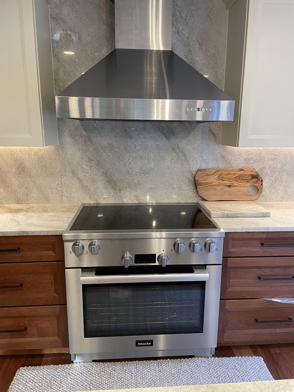 Range with stainless chimney hood and full-height slab backsplash